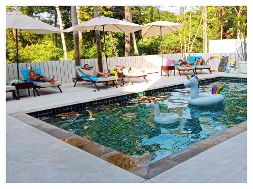 una piscina con cisnes y personas sentadas en sillas en Ampha Place Hotel, en Mae Nam