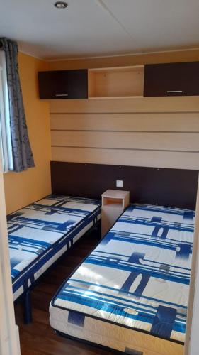 Deux lits se trouvent dans une pièce dotée d’une dans l'établissement Mobil home sur Carnac, à Carnac