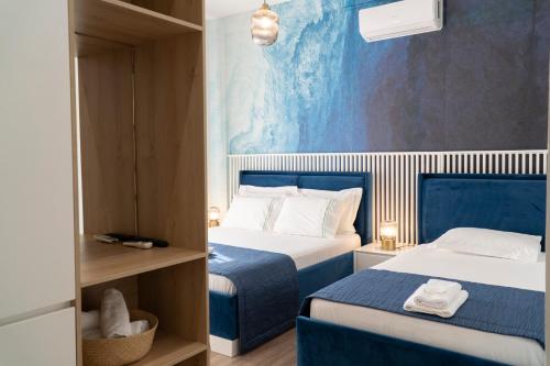 een hotelkamer met 2 bedden en een blauwe muur bij Oyster Apartments in Sarandë