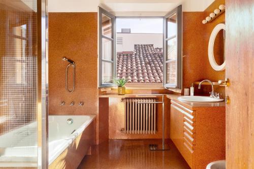 uma casa de banho com uma banheira, um lavatório e uma janela em [Vista Duomo] Cuore di Como em Como