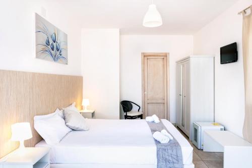 a white bedroom with a bed and a tv at Hotel Aria di Mare in Marina di Ragusa