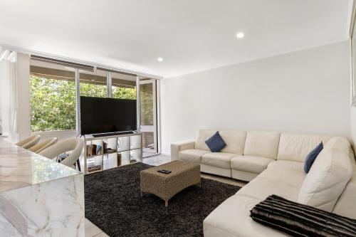 un salon avec un canapé blanc et une télévision dans l'établissement Luxury spacious 3-bedroom Suite on exclusive Lansell Rd, Toorak, à Melbourne