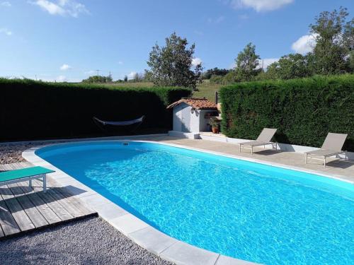- une grande piscine bleue avec 2 chaises à côté dans l'établissement L'échappée verte, à Champdieu