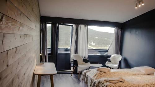 a bedroom with two beds and chairs and a large window at Rondablikk Fjellstasjon in Mysusæter