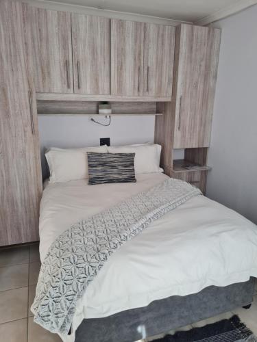 a bedroom with a large white bed with a wooden wall at Mews Road Self-Catering in Queenstown
