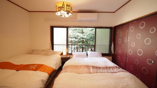 two beds in a room with a window at Open-air bath/11 mins walk from Hakone Yumoto Sta. in Hakone