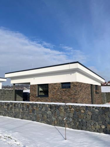 a building with a white roof and a stone wall at Apartmán Nad Přehradou in Frýdek-Místek