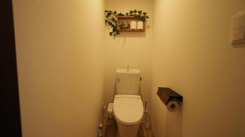 a bathroom with a toilet with a plant on the wall at Open-air bath/11 mins walk from Hakone Yumoto Sta. in Hakone