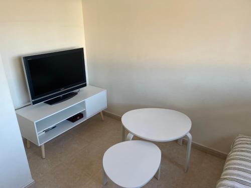 ein Wohnzimmer mit 2 weißen Tischen und einem TV in der Unterkunft Coqueto ático con vistas al mar in Carboneras