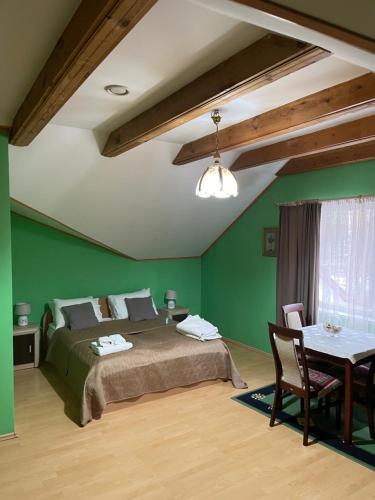 a bedroom with green walls and a bed and a table at Hotel Jerevan in Druskininkai