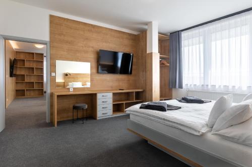 a bedroom with a bed and a desk with a television at Hotel Regent in Třeboň