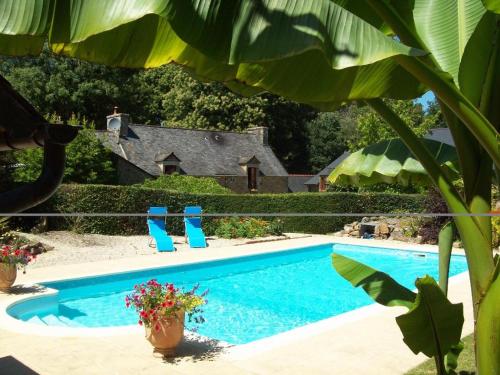 ein Pool mit blauen Stühlen und ein Haus in der Unterkunft La Guyonnais in Quévert