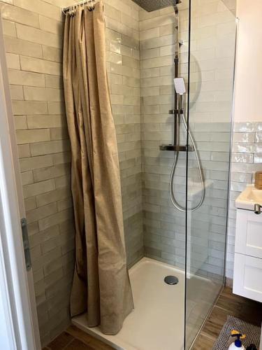 une douche avec une porte vitrée dans une salle de bain dans l'établissement Maison au calme sous les pins, à Moliets-et-Maa