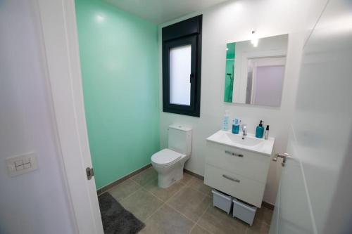 Un baño con inodoro, lavabo y espejo. en Casa joya del Mediterráneo, en Almuñécar