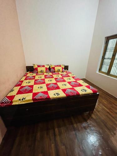 1 dormitorio con 1 cama con un edredón colorido en Ashu Homestay, en Ayodhya
