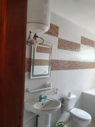 uma casa de banho com um lavatório, um WC e um espelho. em Residence Hadja 03 em Dakar