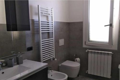baño con lavabo y aseo y ventana en La casa del sole - casa vacanze, en Uri