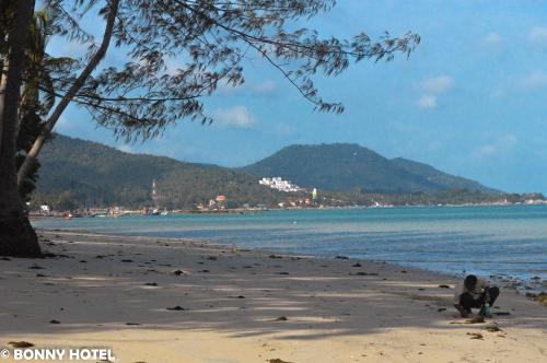 a person sitting on a beach near the water at Bonny Hotel 4 Floors No Elevator in Lamai