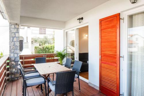 a wooden table and chairs on a balcony with a wooden door at Apartment Tara in Njivice
