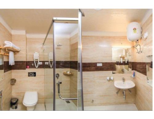 a bathroom with a shower and a toilet and a sink at Hotel Galaxy Grand, Lucknow in Lucknow