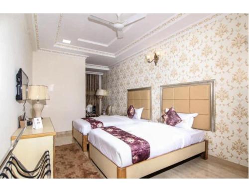 een slaapkamer met 2 bedden en een televisie. bij Hotel Galaxy Grand, Lucknow in Lucknow