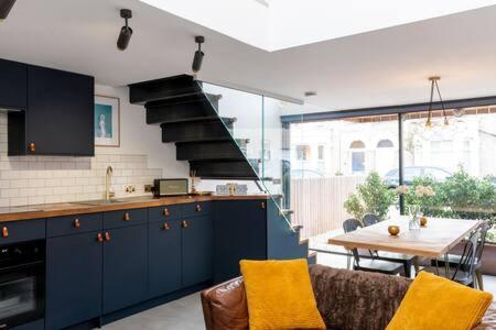 Stylish Cambridge Home with free parking في كامبريدج: مطبخ مع دواليب زرقاء وطاولة مع غرفة طعام