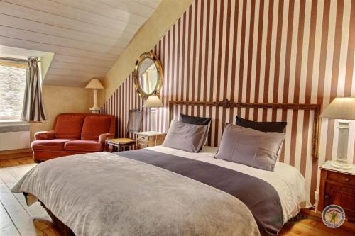 ein Schlafzimmer mit einem großen Bett und einem Stuhl in der Unterkunft La Guyonnais in Quévert