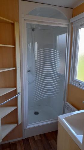 La salle de bains est pourvue d'une douche en verre et d'un lavabo. dans l'établissement Mobil home sur Carnac, à Carnac