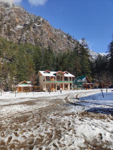 una casa en la nieve frente a una montaña en Avalanche Cottages, en Kasol