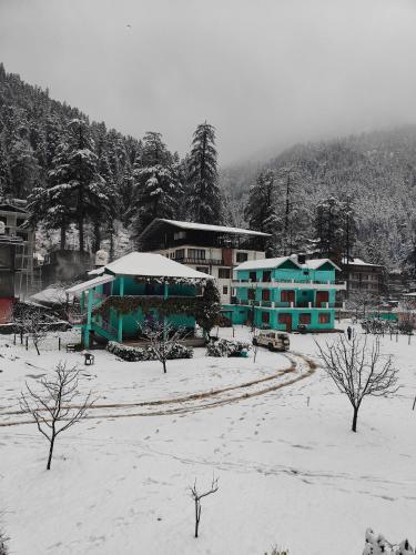 a group of buildings in the snow with trees at Avalanche Cottages in Kasol