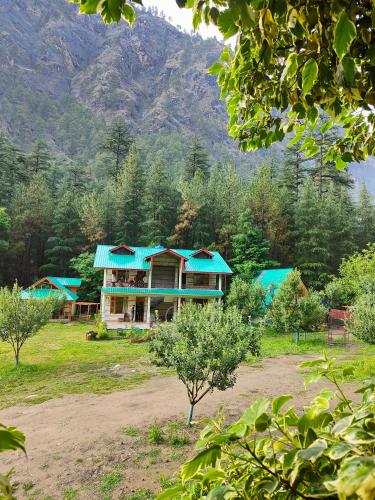 a house with a blue roof with a mountain in the background at Avalanche Cottages in Kasol