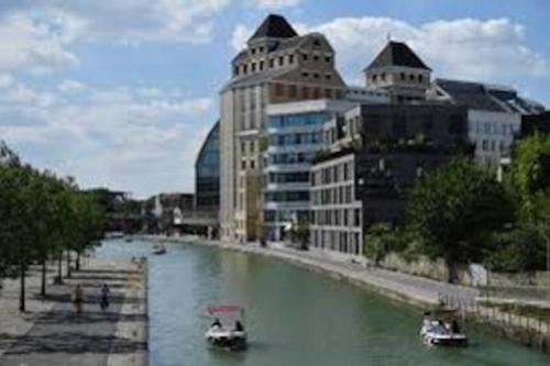 two boats in a river in a city with buildings at Studio number 10 in Pantin