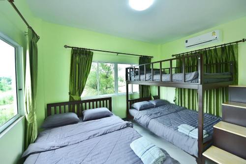 two beds in a room with green walls at พูลวิลล่ากาโป้ บางเสร่ in Bang Sare