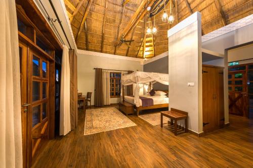a bedroom with a bed in a room with wooden floors at Emburara Farm Lodge in Mbarara
