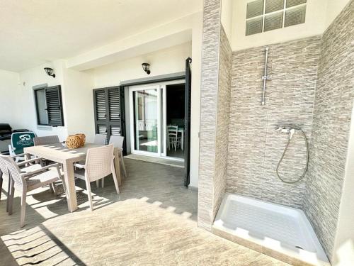 a bathroom with a shower and a table with chairs at Lux Limone - Appartamenti in residence con piscina in Orosei
