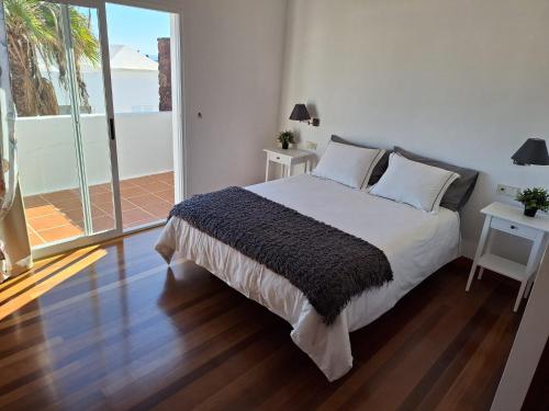 a bedroom with a large bed and a balcony at CASA COSTA VOLCAN in Teguise