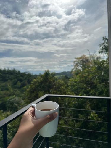 a person holding a cup of coffee on a balcony at Amore Resorts in Kobbekaduwa
