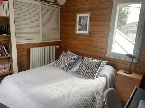 - une chambre avec un lit doté d'oreillers et d'une fenêtre dans l'établissement Maison au calme proche Paris Arena, à Issy-les-Moulineaux