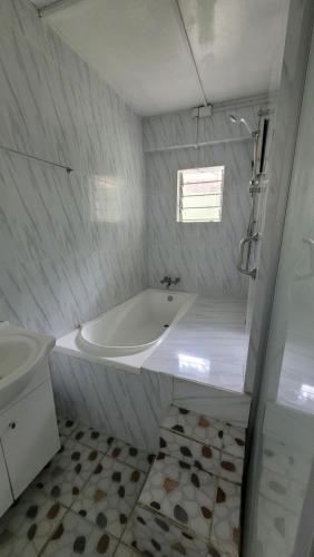 a white bathroom with a tub and a sink at Nomads Nest Fiji in Suva