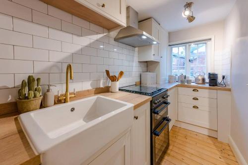 een witte keuken met een wastafel en een fornuis bij Pass the Keys Juno Apartment In the centre of historic Ludlow in Ludlow