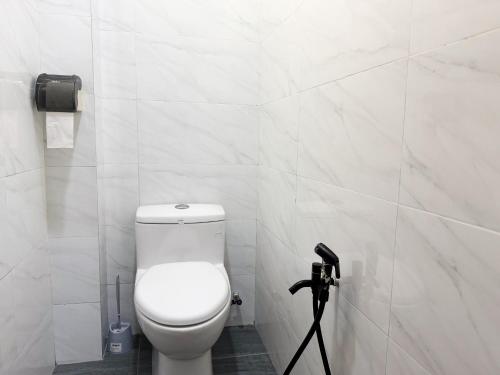 a bathroom with a toilet in a white tiled wall at Inang Street Stay - Cheng Business Park in Melaka