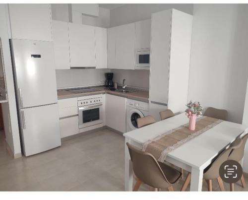 a kitchen with white cabinets and a table with chairs at Martinete Beach Garrucha a 130m de la playa in Garrucha