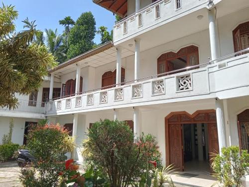 Großes weißes Gebäude mit Balkon in der Unterkunft Power Zone Guest House in Matale