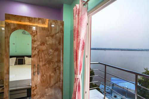 Pokój z balkonem z łóżkiem i oknem w obiekcie River Leaf Inn Taki w mieście Hāsnābād