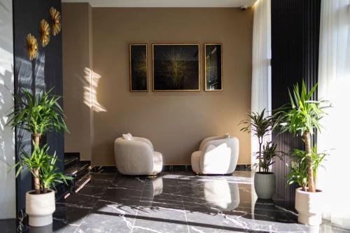 a lobby with two white chairs and potted plants at Destiny Hotel & SPA in Tirana