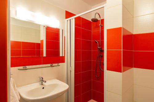 a red and white bathroom with a sink and a shower at Hotel Regent in Třeboň