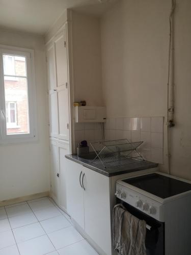 une cuisine blanche avec une cuisinière et une fenêtre dans l'établissement Maud’s apppartment, à Asnières-sur-Seine