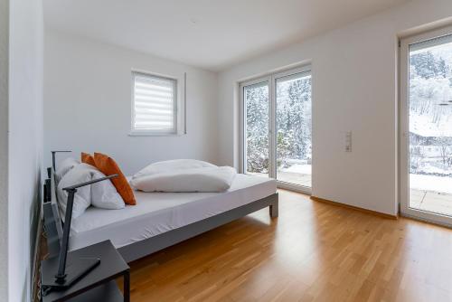 a white bedroom with a bed and a television at Schmittenhöhe Lodge in Zell am See