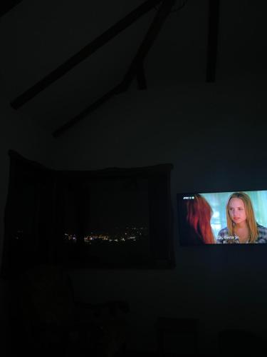 a television screen in a dark room with a woman on it at Apartmani Mladenovac in Mladenovac