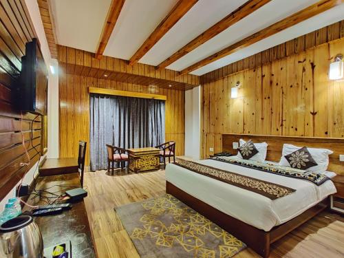a bedroom with a large bed in a room with wooden walls at Hotel Vajra in Tawang